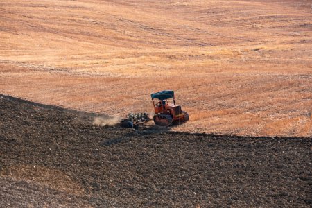 Tractor working on farming lands, countryside landscape