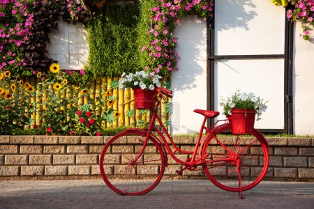 Téléchargez les photos : Vélo rouge avec des fleurs dans un beau jardin - en image libre de droit