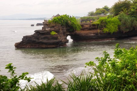 Téléchargez les photos : Arc rocheux avec un temple et des plantes vertes sur l'île de Bali, Indonésie - en image libre de droit