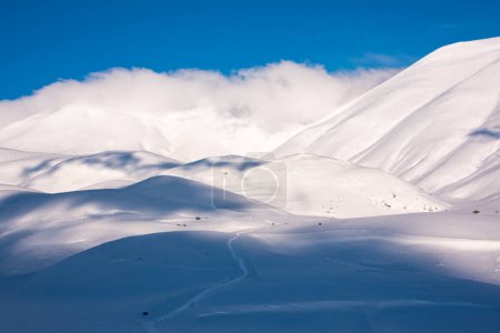 Foto de Hermosa luz del sol y tonos de contraste en las colinas de nieve y nubes - Imagen libre de derechos