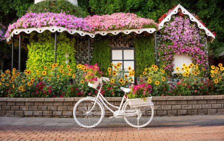 Téléchargez les photos : Vélo blanc avec des fleurs dans un beau jardin - en image libre de droit