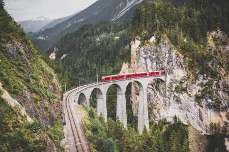 Téléchargez les photos : Train rouge suisse sur viaduc en montagne pour une randonnée pittoresque - en image libre de droit