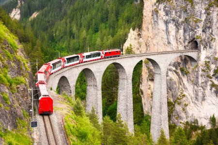 Téléchargez les photos : Train rouge suisse sur viaduc en montagne pour une randonnée pittoresque - en image libre de droit