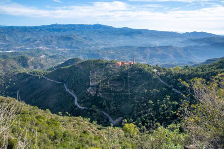 Téléchargez les photos : Vue du monastère de Sant Benet de Montserrat d'en haut. L'air est légèrement brumeux. Le monastère est situé au milieu de la nature verte. Vous pouvez voir clairement la montagne de Monterserrat, sur laquelle se dresse le monastère et les routes d'accès. - en image libre de droit