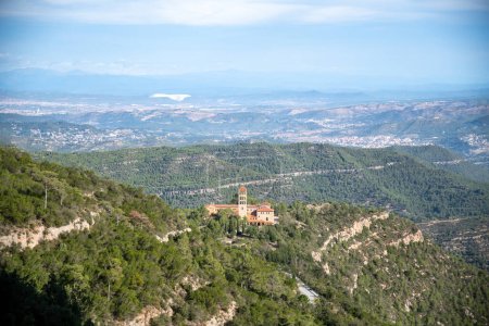 Téléchargez les photos : Vue du monastère de Sant Benet de Montserrat d'en haut. L'air est légèrement brumeux. Le monastère est situé au milieu de la nature verte. La montagne de Monterserrat, sur laquelle se dresse le monastère, est clairement visible. - en image libre de droit