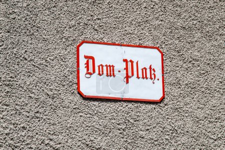 Photo for A white sign with the inscription Dom-Platz on a gray house wall. The sign has a red border and red old German lettering. - Royalty Free Image