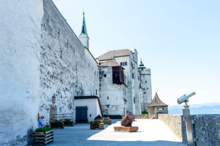 Téléchargez les photos : Salzbourg, Salzbourg - Autriche - 17-06-2021 : Mur médiéval de la forteresse Hohensalzburg avec canon, télescope et flèche contre un ciel clair - en image libre de droit