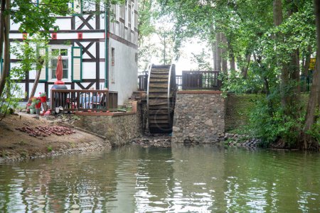 Foto de Wusterhausen, Brandeburgo - Alemania - 28-06-2022: Una rueda de molino al final de un río en una casa de madera. El río tiene agua verde y la casa es una casa de entramado. - Imagen libre de derechos
