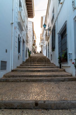 Téléchargez les photos : Altea, Alicante - Espagne - 01-05-2024 : Des marches pavées traversent des bâtiments aux murs blancs dans les charmantes rues d'Altea - en image libre de droit