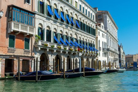 Venedig, Venetien - Italien - 06-10-2021: Charmanter venezianischer Palast mit blauen Markisen und festgemachten Booten
