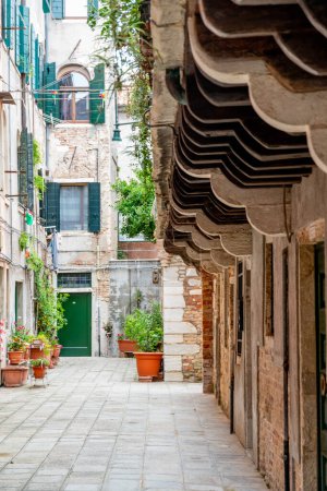 Venecia, Véneto - Italia - 06-10-2021: Callejón pavimentado flanqueado por techos colgantes tradicionales en Venecia, Italia