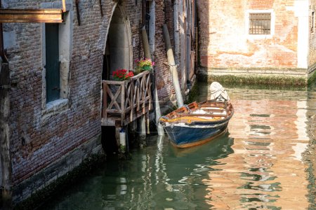 Venecia, Véneto - Italia - 06-10-2021: Pequeño barco atado al lado de un encantador balcón con flores en Venecia