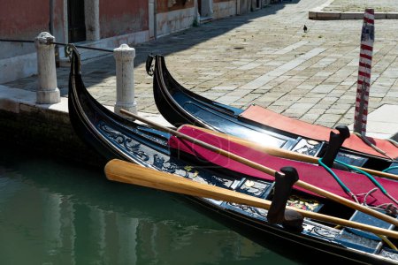 Venice, Veneto - Italy - 06-09-2021: Elegant gondolas tied up along the canal in Venice, Italy