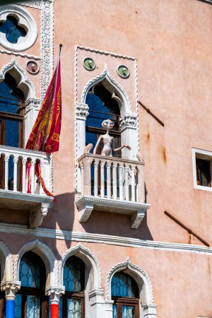 Téléchargez les photos : Venise, Vénétie - Italie - 06-10-2021 : Une scène de balcon unique avec une figure étrangère dans l'architecture gothique de Venise - en image libre de droit