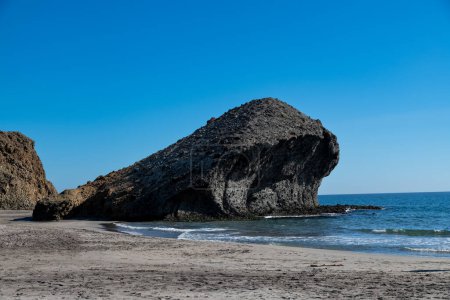 Cabo de Gata, Almería - España - 23-01-2024: Formaciones rocosas siluetas y mar espumoso bajo la brillante luz del sol en Cabo de Gata