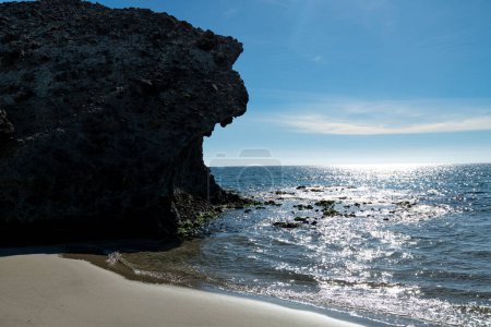 Cabo de Gata, Almería - España - 23-01-2024: Formaciones rocosas siluetas y mar espumoso bajo la brillante luz del sol en Cabo de Gata