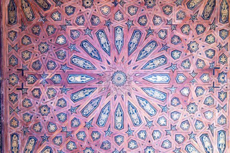 Stunning red, blue and golden geometric star patterns cover a ceiling in the Alhambra Palace