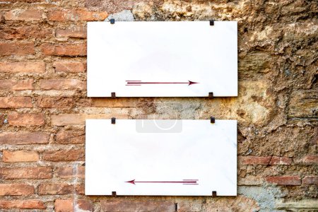 Dos carteles vacíos con una flecha izquierda y una flecha derecha cada uno, en una pared de la casa sin enlucir para autoetiquetarse.