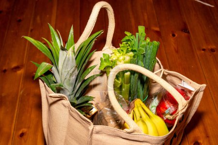 Bolsa ecológica repleta de verduras frescas, frutas y productos esenciales de la despensa