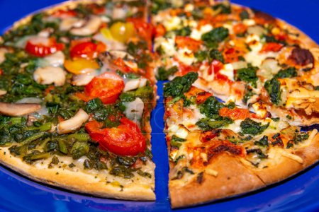 Una vibrante pizza vegetariana con tomates, espinacas y setas en un plato azul, uno listo para comer