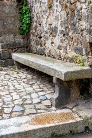 Bautzen, Saxony - Germany - 04-10-2021: Aged stone bench nestled beside a cobblestone walkway and rustic wall