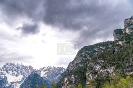 Alpen, South Tyrol - Italy - 06-07-2021: Close-up of dark clouds looming over partly snow-covered mountain peaks in the Alps, creating a dramatic scene