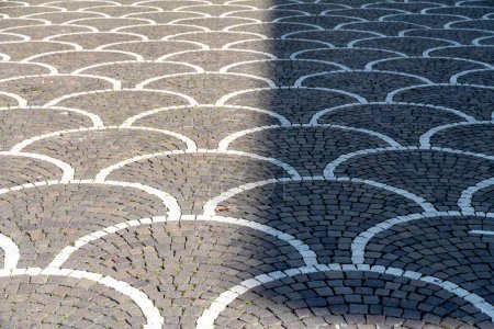 Téléchargez les photos : Trévise, Vénétie - Italie - 06-08-2021 : Des pavés géométriques attrayants avec des arcs entrelacés de pavés gris et blancs à moitié ensoleillés et à moitié ombragés - en image libre de droit