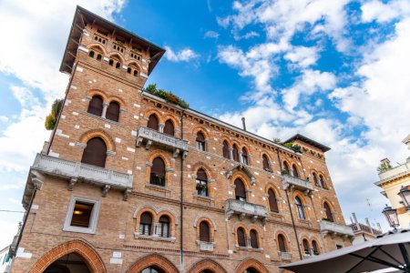 Foto de Treviso, Venetien - Italia - 06-08-2021: Edificio histórico de ladrillo rojo con ventanas románicas, balcones y columnas, ubicado en Piazza San Vito, Treviso, Italia - Imagen libre de derechos