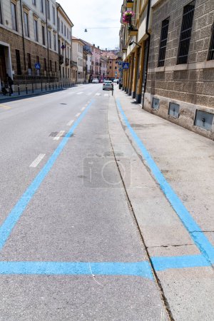 Téléchargez les photos : Vicence, Venetien - Italie - 06-12-2021 : Une rue dans une ville avec un long parking payant marqué par des lignes bleues, avec une voiture garée au loin et flanqué de bâtiments historiques - en image libre de droit