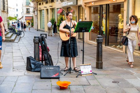 Foto de Vicenza, Venetien - Italia - 06-12-2021: Un músico con una guitarra, un altavoz y un cartel con una dirección de Instagram canta a los transeúntes en la zona peatonal de Vicenza - Imagen libre de derechos