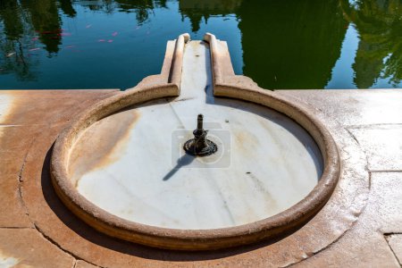 Foto de Granada, Granada - España - 30-01-2024: Fuente de mármol circular en El Partal con vistas a un tranquilo estanque en la Alhambra, que refleja la belleza de la arquitectura nazarí - Imagen libre de derechos