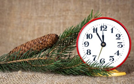 Foto de Reloj de Año Nuevo en estilo retro, sobre el fondo de ramas de árboles de Navidad y conos de pino. descubrimiento de felicitaciones - Imagen libre de derechos