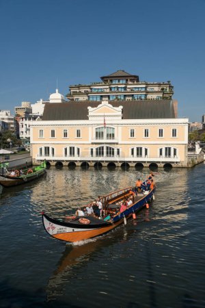 Téléchargez les photos : AVEIRO, PORTUGAL - 30 AOÛT 2019 : Ancien bâtiment de capitainerie dans le canal central d'aveiro avec les bateaux moliceiro traditionnels, Région de Beira, Portugal. - en image libre de droit
