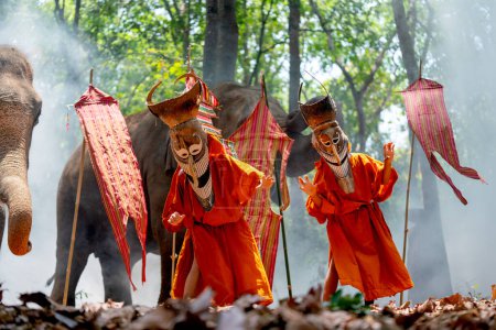 Photo for Two boy wear Pee Ta Khon, traditional culture art as ghost of Asian culture, dress and action to show horror position and elephants stand in the background also with flags. - Royalty Free Image