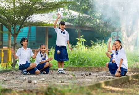 Foto de Grupo de niña asiática disfrutar de jugar petanca en el área de patio de arena como campo de deporte con acción de animar y motivar a ganar el juego. - Imagen libre de derechos