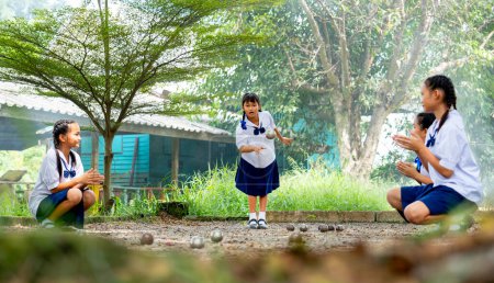 Foto de Grupo de niña asiática disfrutar de jugar petanca en el área de patio de arena como campo de deporte con acción de animar y motivar a ganar el juego. - Imagen libre de derechos
