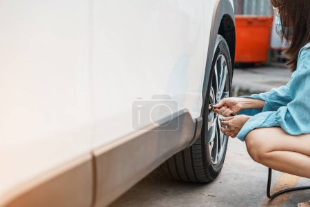 Photo for Woman driver hand inflating tires of vehicle, removing tire valve nitrogen cap for checking air pressure and filling air on car wheel at gas station. self service, maintenance and safety - Royalty Free Image