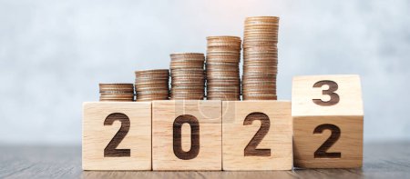 voltear 2022 a 2023 bloque de año con la pila de monedas. Conceptos de dinero, presupuesto, impuestos, inversión, finanzas, ahorro y resolución de año nuevo