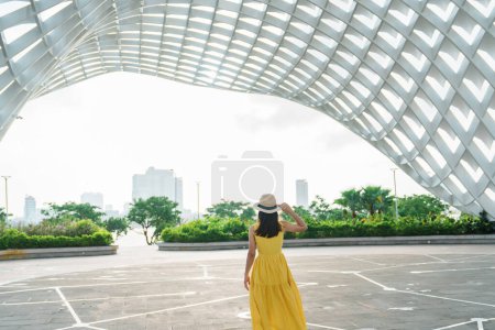 Foto de Mujer viajera con vestido amarillo visitando la ciudad de Da Nang. Turismo visitando el edificio de la ciudad. Monumento y popular para la atracción turística. Vietnam y el sudeste asiático concepto de viaje - Imagen libre de derechos