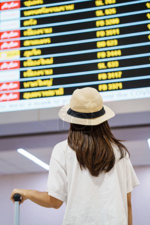 Foto de Manija de equipaje de mano de mujer joven antes de facturar el tiempo de vuelo en el aeropuerto, transporte, seguros, viajes y conceptos de vacaciones - Imagen libre de derechos