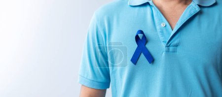 Téléchargez les photos : Mars Mois de sensibilisation au cancer colorectal, Femme tenant un ruban bleu foncé pour soutenir les personnes vivant et malades. Santé, espoir et concept de Journée mondiale contre le cancer - en image libre de droit