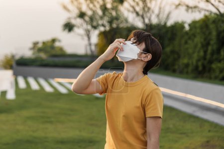 Téléchargez les photos : Jeune femme asiatique portant un masque respiratoire N95 protéger et filtrer pm2.5 ou particules contre la pollution atmosphérique mauvaise dans la ville. Indice de Qualité de l'Air, IQA, Malsain, concept de soins de santé - en image libre de droit