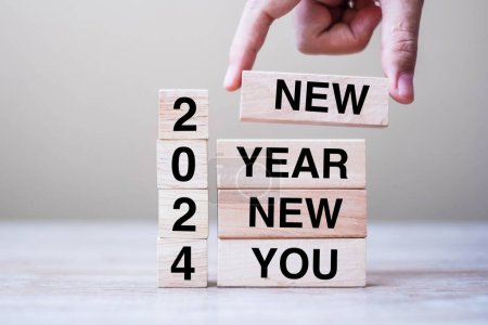 Hand hält Holzblock mit Text 2024 NEW YEAR NEW YOU auf Tischhintergrund. Auflösung, Strategie, Ziel, Geschäfts- und Urlaubskonzepte