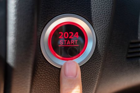Téléchargez les photos : Finger appuyez sur un bouton d'allumage de voiture avec 2024 START texte à l'intérieur de l'automobile. Nouvel An Nouveau Vous, prévision, résolution, motivation, changement, objectif, vision, innovation et concept de planification - en image libre de droit