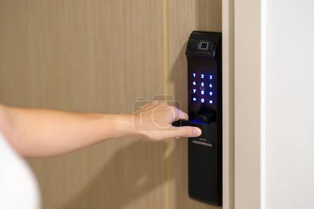 Photo for Hand using smart digital door lock while open or close the door at home or apartment. NFC Technology, Fingerprint scan, keycard, PIN number, smartphone, electrical and contactless lifestyle concepts - Royalty Free Image
