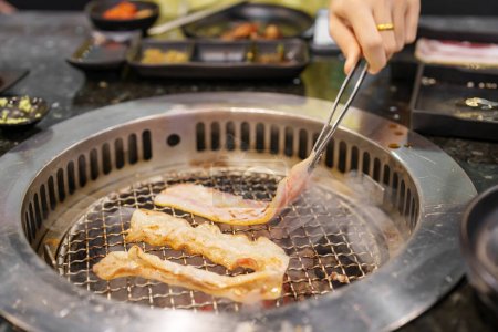 Hand Grillen Schweinefleisch auf Herd servieren im Restaurant. Japanisches Essen und koreanischer BBQ-Stil