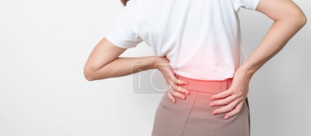 erwachsene Hündin mit Muskelschmerzen auf grauem Hintergrund. Ältere Frau mit Rückenschmerzen aufgrund des Piriformis-Syndroms, Rückenschmerzen und Kompression der Wirbelsäule. Bürosyndrom und medizinisches Konzept