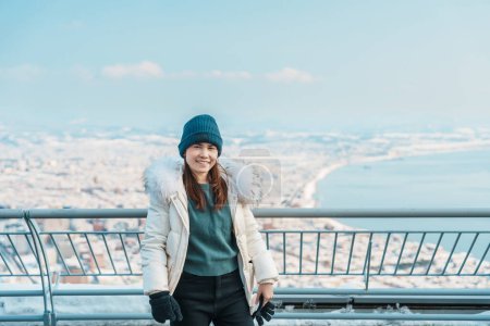 Touristin zu Besuch in Hakodate, Reisende im Pullover Sightseeing-Blick vom Hakodate Berg mit Schnee im Winter. Wahrzeichen und beliebt für Attraktionen in Hokkaido, Japan. Reise- und Urlaubskonzept