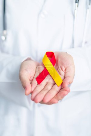 Photo for Doctor holding Red and Yellow ribbon. World hepatitis day awareness month, 28 July, Liver cancer, Jaundice, Cirrhosis, Failure, Enlarged, Hepatic Encephalopathy and Health concept - Royalty Free Image