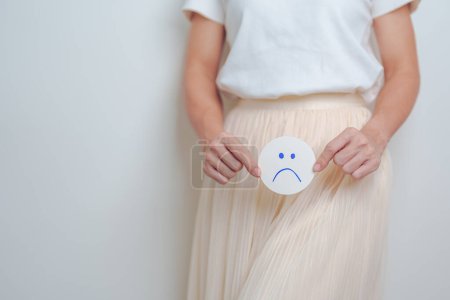 Photo for Woman hold Bad and unhappy Face paper over abdomen. Ovarian and Cervical cancer, Endometriosis, Hysterectomy, Uterine, Reproductive, menstruation, Infertility, Pregnancy and Sexual Transmitted disease - Royalty Free Image